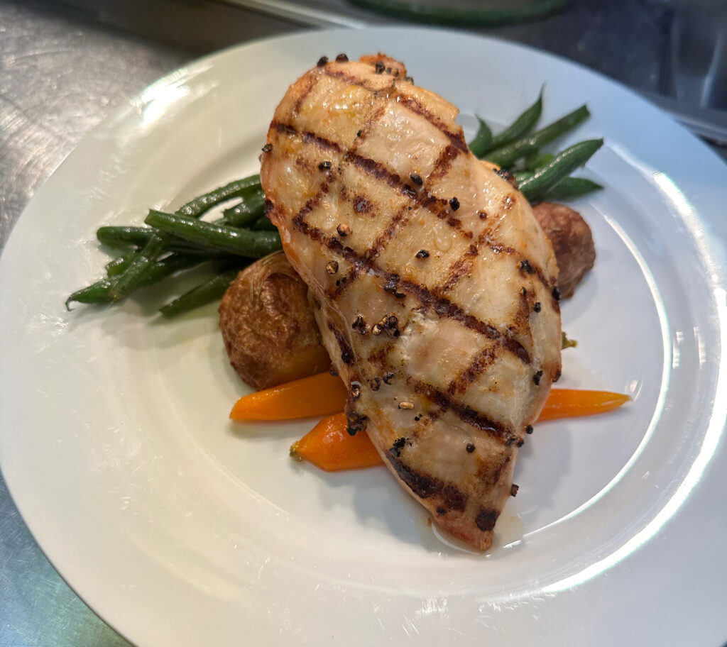 Chicken breast on a plate with grilled vegetable and fingerling potatoes